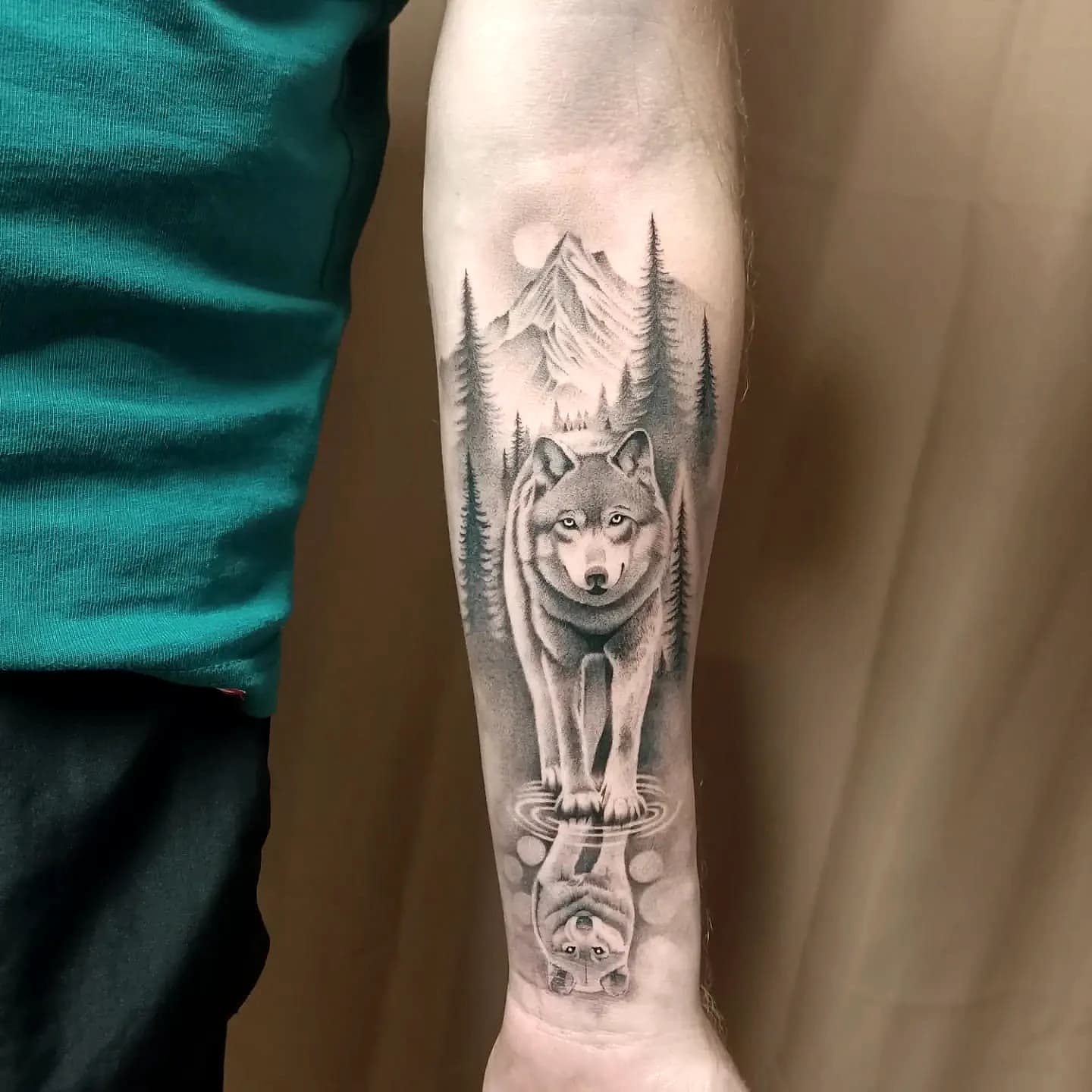 Tatouage réaliste loup, forêt de montagne et reflet sur l'avant-bras, ProSkin-R Cahors